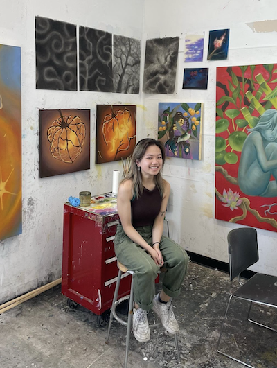 Connie sitting on a stool in her painting studio.